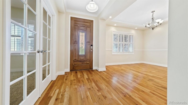 foyer featuring ornamental molding, wood-type flooring, and a notable chandelier