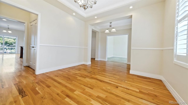 spare room with an inviting chandelier, crown molding, and wood-type flooring