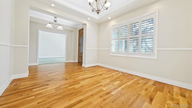 spare room with hardwood / wood-style floors and an inviting chandelier