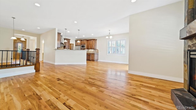 unfurnished living room featuring an inviting chandelier and light hardwood / wood-style flooring