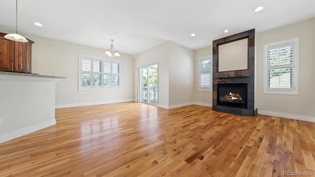 unfurnished living room with a notable chandelier, light hardwood / wood-style floors, and a large fireplace