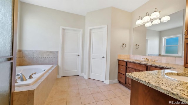 bathroom featuring tiled tub, vanity, and tile patterned floors