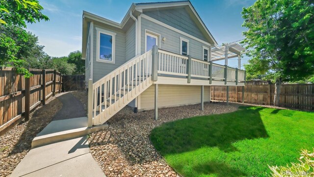 back of house featuring a wooden deck, a yard, and a pergola