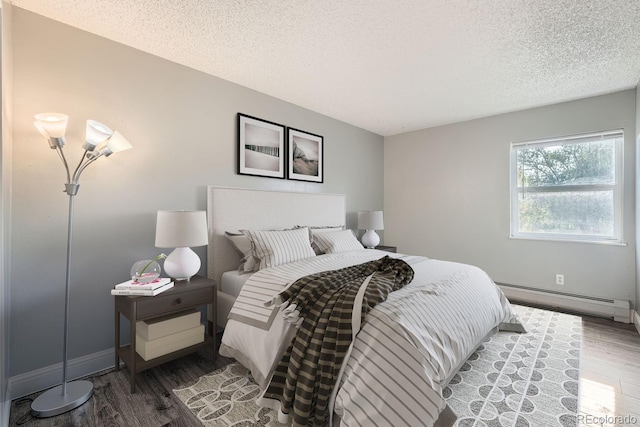 bedroom with baseboards, a textured ceiling, a baseboard heating unit, and wood finished floors