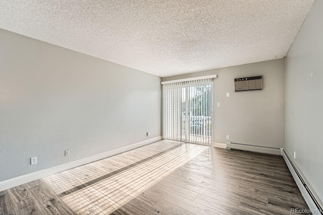 spare room featuring a textured ceiling, a wall mounted AC, a baseboard radiator, and wood finished floors