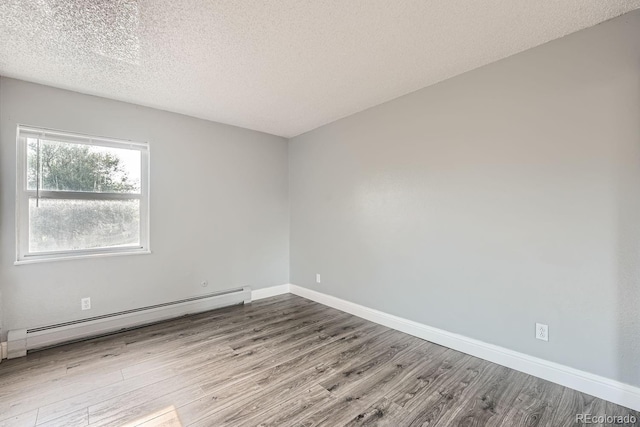 empty room with a baseboard radiator, a textured ceiling, baseboards, and wood finished floors