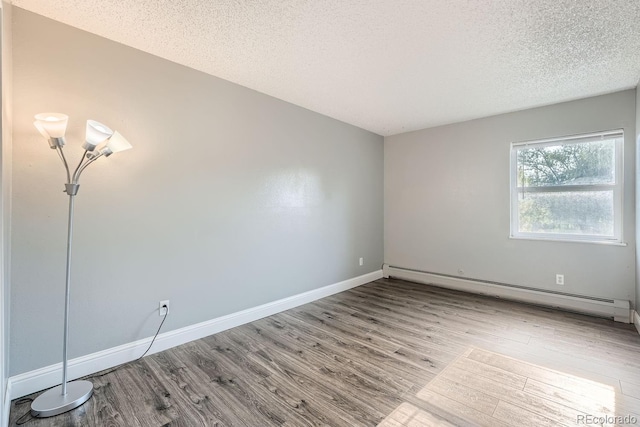 unfurnished room with a baseboard radiator, a textured ceiling, baseboards, and wood finished floors