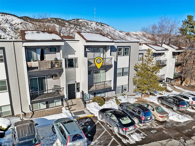 snow covered building with uncovered parking and a mountain view