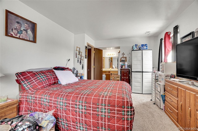 bedroom featuring light carpet and ensuite bath