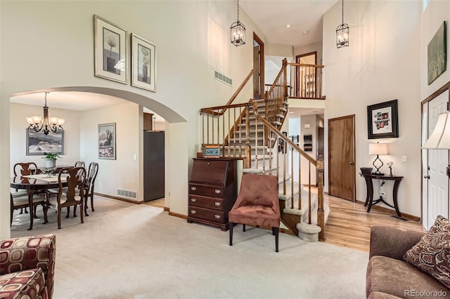 9791 Sterling Dr, Highlands Ranch, CO 80126 - carpeted living area with arched walkways, a high ceiling, stairway, and a chandelier