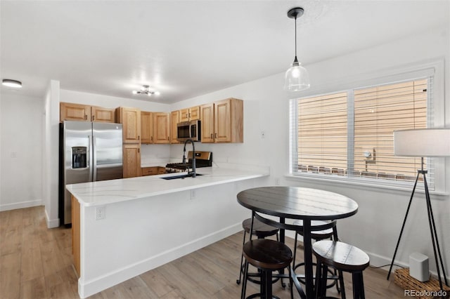 7654 Crestone Peak Trl, Colorado Springs, CO 80924 - kitchen with appliances with stainless steel finishes, a peninsula, light wood-type flooring, baseboards, and a sink