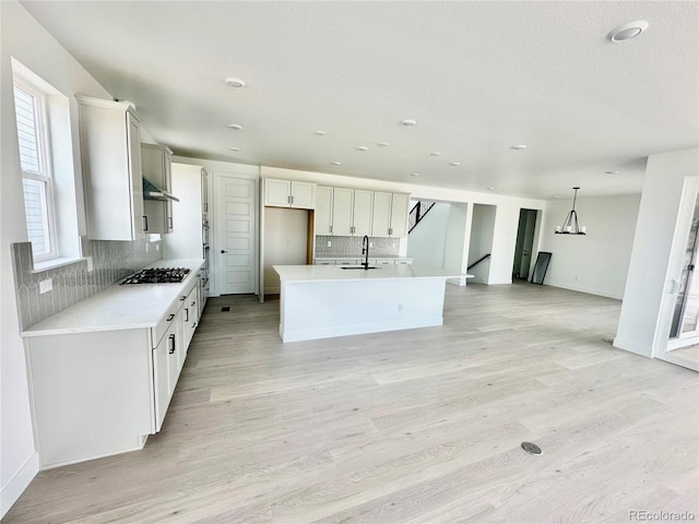 16521 Black Rose Cir, Parker, CO 80134 - kitchen featuring extractor fan, gas cooktop, decorative backsplash, light wood finished floors, and recessed lighting