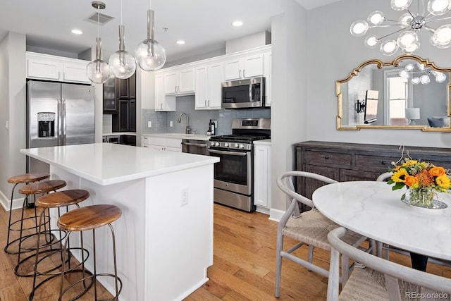 1631 N Emerson St Unit 321, Denver, CO 80218 - kitchen with stainless steel appliances, a kitchen breakfast bar, visible vents, and white cabinetry