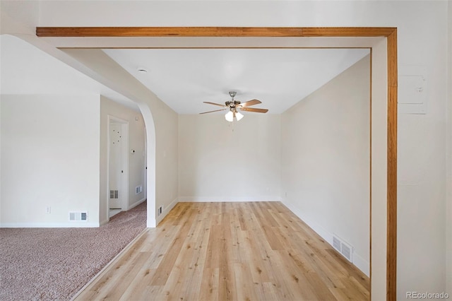 unfurnished room featuring arched walkways, ceiling fan, visible vents, and baseboards