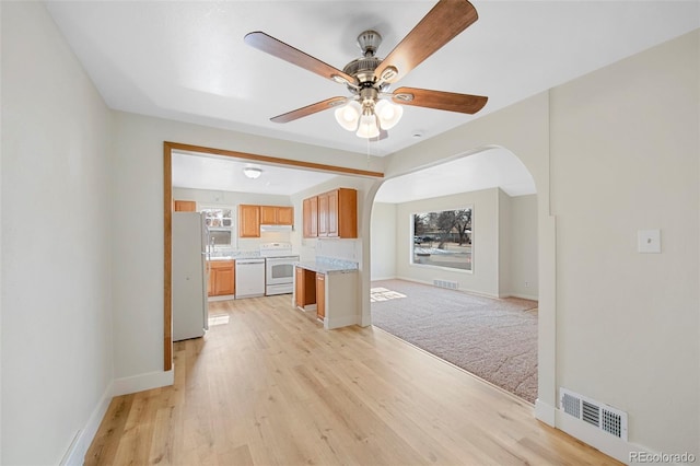 kitchen featuring white appliances, visible vents, arched walkways, open floor plan, and light countertops