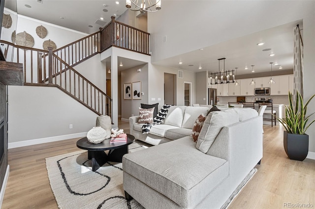 living room featuring a high ceiling, light wood-type flooring, and a chandelier