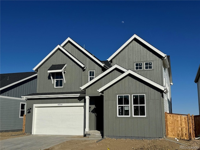 view of front facade featuring a shingled roof, concrete driveway, an attached garage, and fence