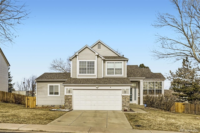 traditional-style home featuring stone siding, fence, roof with shingles, concrete driveway, and a garage