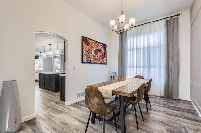 dining room featuring light wood finished floors, a chandelier, baseboards, and visible vents