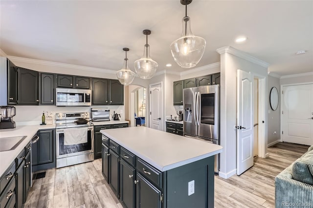 kitchen featuring ornamental molding, light countertops, light wood-style floors, appliances with stainless steel finishes, and a center island