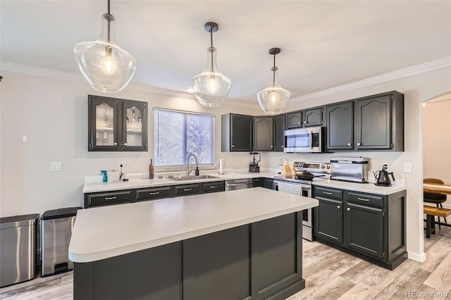 kitchen with ornamental molding, a sink, light wood-style floors, appliances with stainless steel finishes, and light countertops