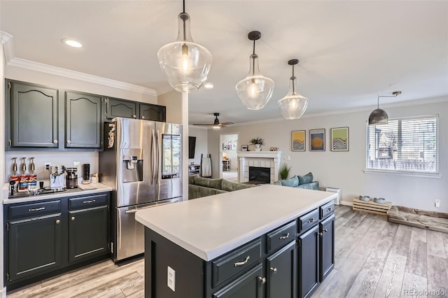 kitchen with light wood finished floors, stainless steel fridge with ice dispenser, open floor plan, light countertops, and ornamental molding