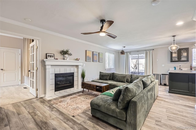 living area with light wood-style flooring, crown molding, and a ceiling fan