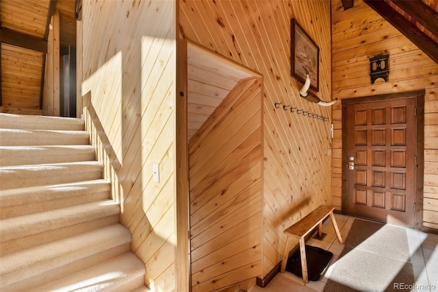 stairs featuring a towering ceiling and wood walls