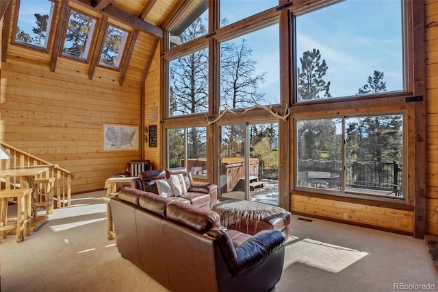 carpeted living room featuring a skylight, wooden ceiling, wooden walls, and high vaulted ceiling