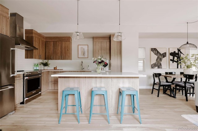 kitchen featuring wall chimney exhaust hood, a center island, appliances with stainless steel finishes, and pendant lighting