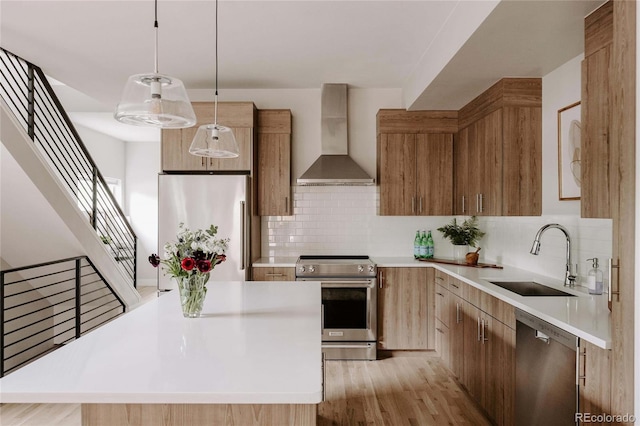 kitchen featuring pendant lighting, a center island, sink, wall chimney range hood, and stainless steel appliances