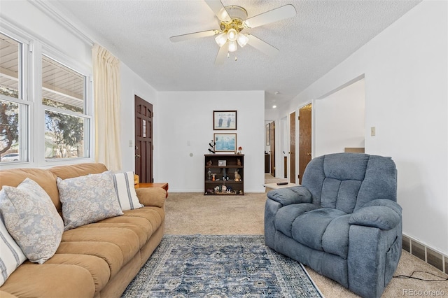 living room with a ceiling fan, light colored carpet, visible vents, and a textured ceiling