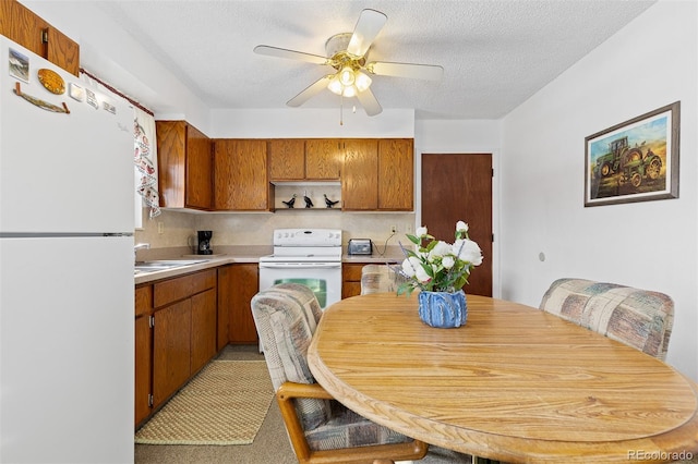 kitchen featuring a textured ceiling, light countertops, white appliances, and brown cabinets