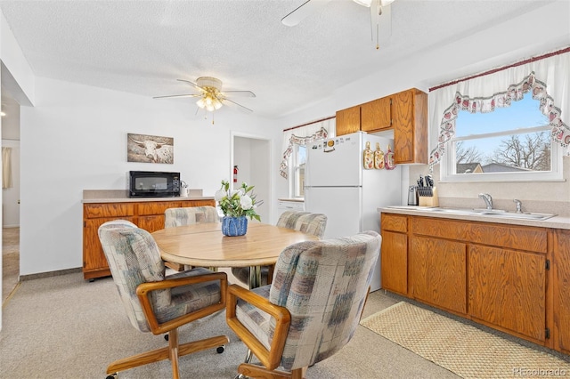 dining area featuring light colored carpet, ceiling fan, and a textured ceiling