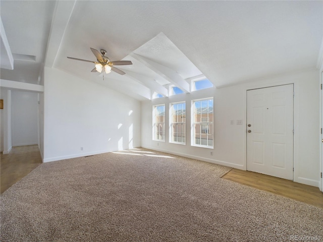 unfurnished living room with lofted ceiling with beams, ceiling fan, and carpet