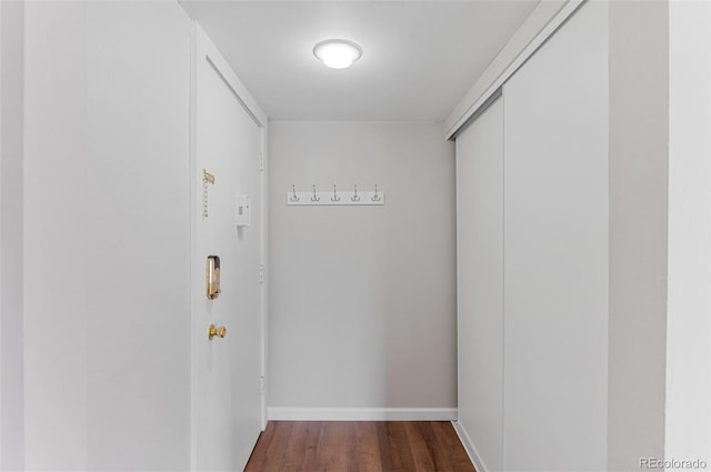 corridor with baseboards and wood finished floors