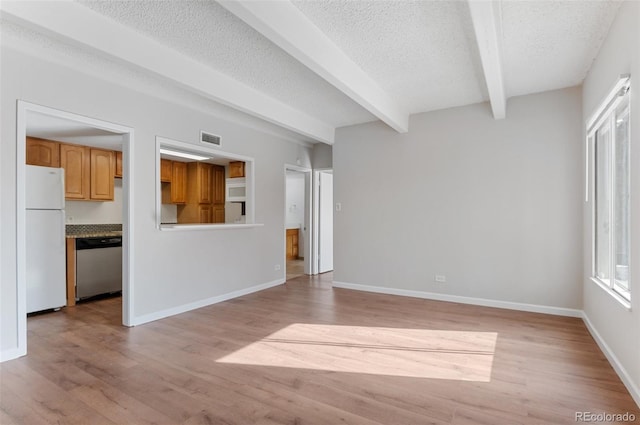 unfurnished living room featuring baseboards, beamed ceiling, visible vents, light wood finished floors, and a textured ceiling