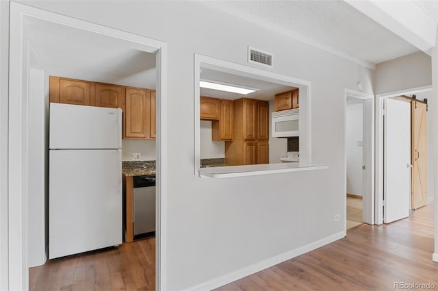 kitchen featuring white appliances, visible vents, light wood-style flooring, and baseboards