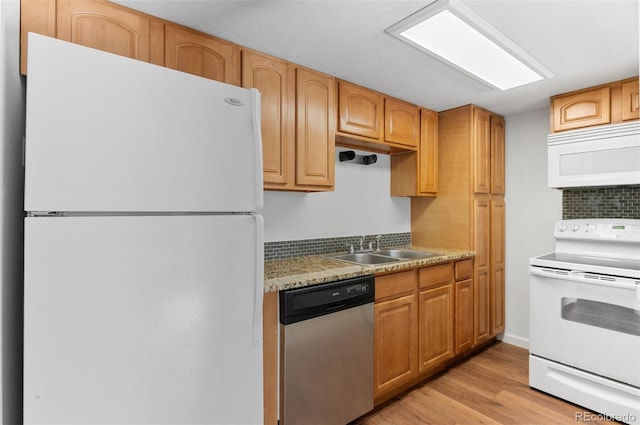 kitchen with white appliances, light wood-style floors, and a sink