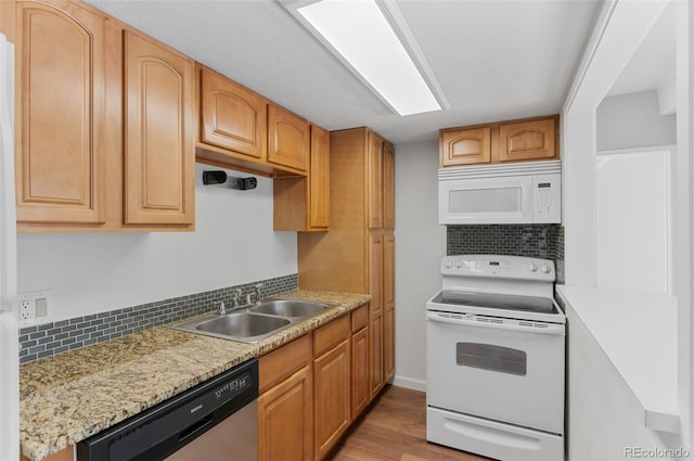 kitchen with white appliances, light wood-style floors, decorative backsplash, and a sink