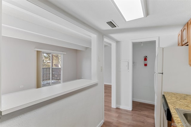 hallway featuring visible vents, a sink, light wood-style flooring, and baseboards