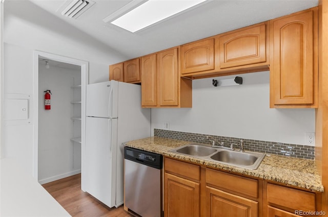 kitchen with light wood-style flooring, freestanding refrigerator, dishwasher, visible vents, and a sink