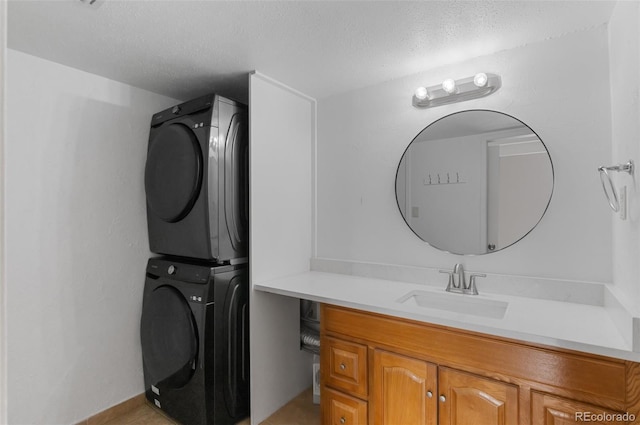 bathroom with stacked washer / dryer, vanity, and a textured ceiling