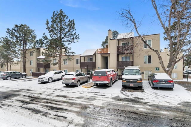 snow covered parking area featuring uncovered parking and a residential view