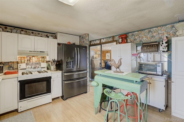 41215 Alta Vista Rd, Ramah, CO 80832 - kitchen with light wood-type flooring, white cabinetry, white range with gas stovetop, under cabinet range hood, and refrigerator with ice dispenser