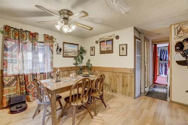 41215 Alta Vista Rd, Ramah, CO 80832 - dining room featuring light wood-type flooring, wooden walls, a textured ceiling, a ceiling fan, and wainscoting