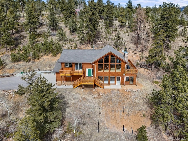 rear view of property featuring a wooded view and a chimney