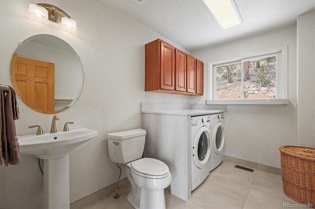 washroom featuring visible vents, baseboards, laundry area, a sink, and independent washer and dryer