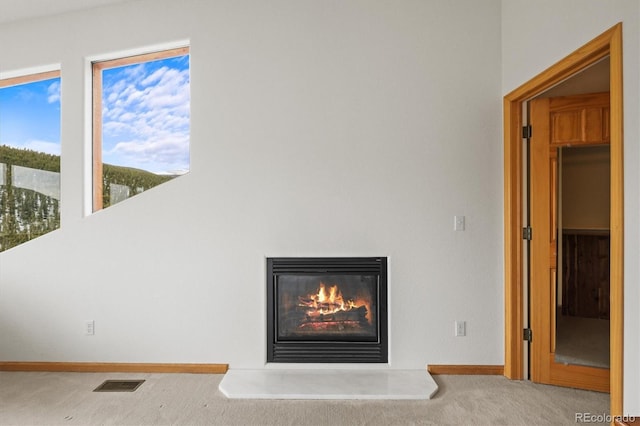 details with visible vents, baseboards, carpet, and a glass covered fireplace