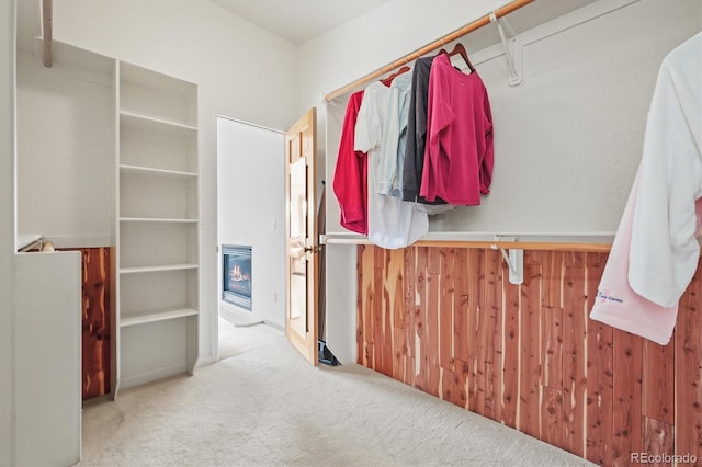 spacious closet featuring a glass covered fireplace and carpet floors